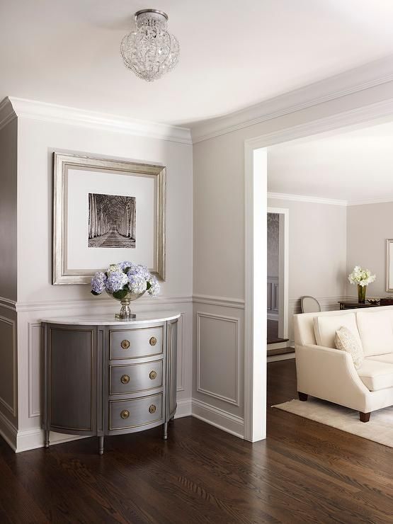 Chic foyer features upper walls painted pale gray and lower walls clad in light ...