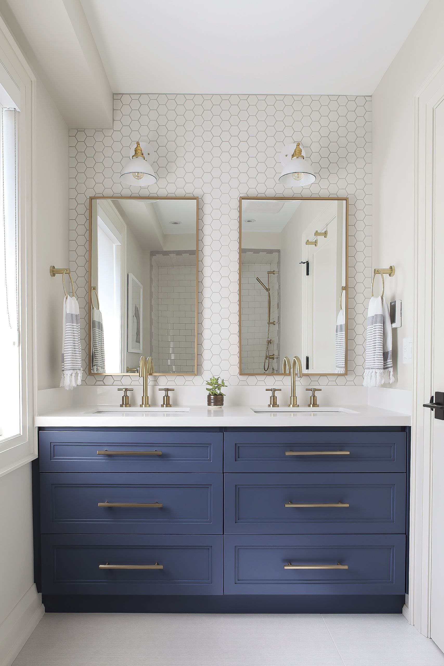 Deep blue painted cabinets in an otherwise all white bathroom