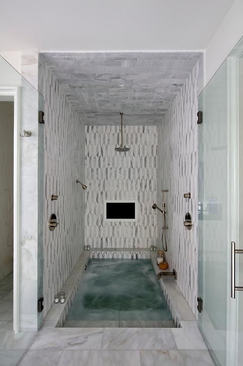 Stunning spa shower boasts white and gray marble tiles and ceiling fitted with a…