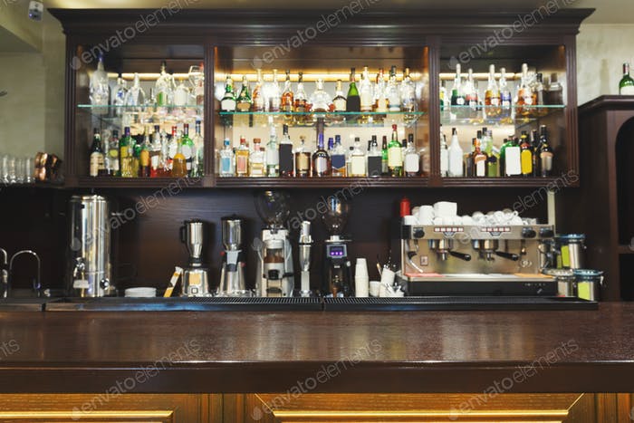 Bar counter with alcohol bottles assortment photo by Prostock .