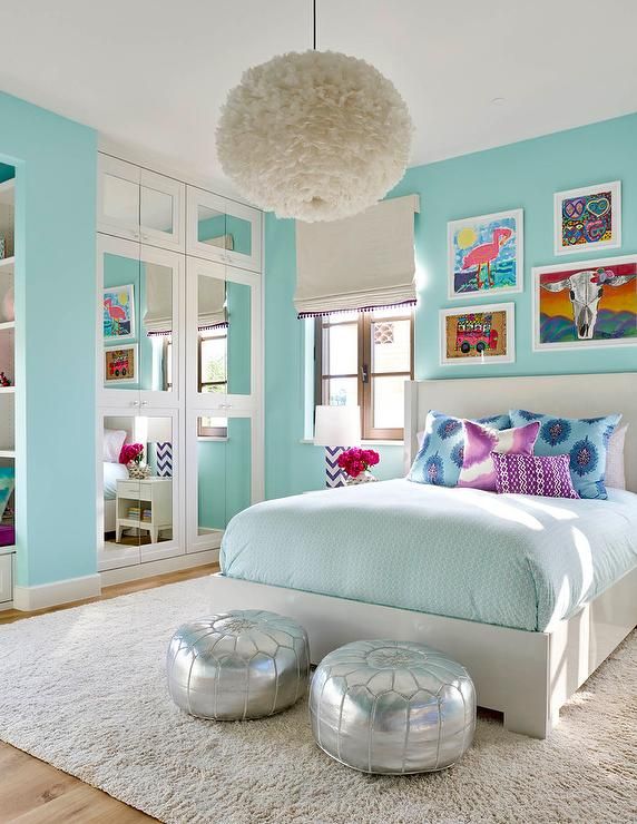 Turquoise blue girl's bedroom features a white feather chandelier .